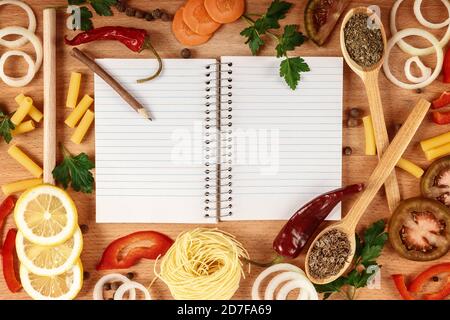 Set di verdure e frutta a fette, con spezie e un libro di cucina su un tagliere. Foto Stock