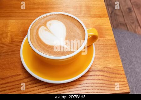 Tazza di caffè giallo con latte art a forma di cuore Foto Stock