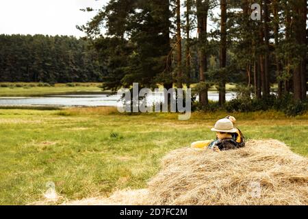 ragazzino in un cappello sdraiato su un pagliaio nel campo. Campagna d'autunno. Foto Stock