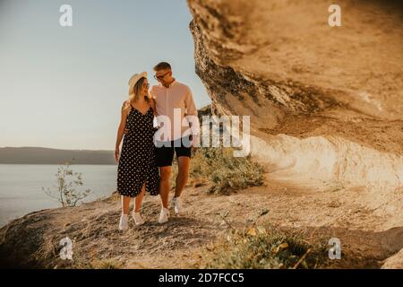 l'uomo e la donna in cappello camminano lungo le rocce sopra il scogliera Foto Stock
