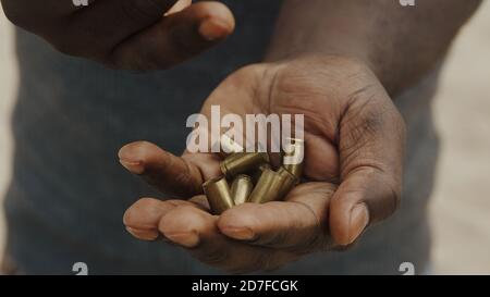 Primo piano, mano nera dell'uomo che conta i proiettili usati. Molti casi di proiettile sono stati trasferiti da una mano all'altra. Foto di alta qualità Foto Stock