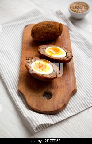 Uova di Scotch fatte in casa su una rustica tavola di legno, vista laterale. Foto Stock