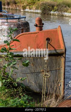 una chiatta arrugginita di vecchio canale o imbarcazione da lavoro stretta galleggiante sul canale grand union vicino a braunston nel northamptonshire, regno unito Foto Stock