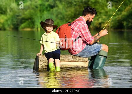 Pesca del Padre e del Figlio - tempo di famiglia insieme. Felice padre e figlio che pesca nel fiume che tiene canne da pesca. Foto Stock