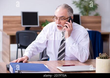 Anziano dipendente che soffre di radicolite sul posto di lavoro Foto Stock