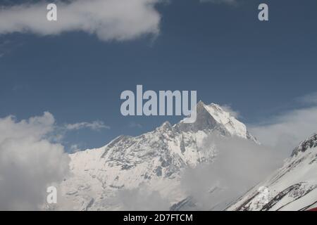 Maestoso scatto di un massiccio roccioso innevato Annapurna con picchi nelle nuvole, Nepal, Himalaya Foto Stock