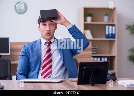 Giovane dipendente che indossa occhiali virtuali in ufficio Foto Stock