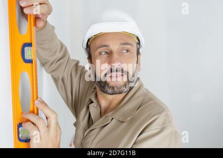 tradesman che usa la livella di spirito sulla parete Foto Stock