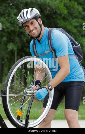 uomo che ripara una bicicletta all'aperto Foto Stock