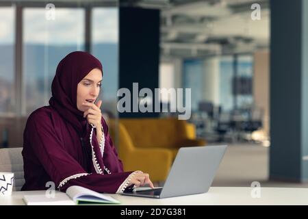 Donna d'affari astica penosa seduta sul posto di lavoro in ufficio Foto Stock