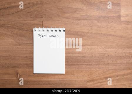 Pagina vuota di un taccuino per annotare le risoluzioni per il nuovo anno, 2021, su una scrivania di legno, con spazio di copia Foto Stock