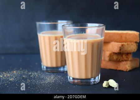 Snack Tea Time - il sano frusto di grano servito con tè indiano caldo masala, su sfondo nero con il cardamomo. Anche noto come Mumbai taglio chai. Foto Stock