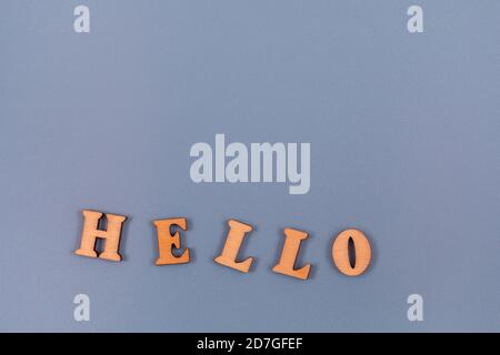 Ciao parola scritta in lettere alfabetiche di legno su uno sfondo grigio. Testo sulla tabella per la progettazione o il concetto. Foto Stock