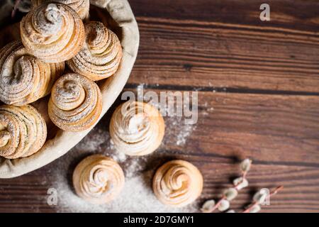 Le deliziose cruffine moderne sono realizzate con croissant in puff sotto forma di muffin. Cruffine con cesto di legno su fondo di legno scuro, spruzzate Foto Stock