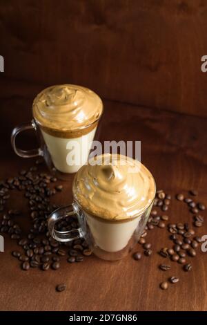 caffè di algone freddo in bicchieri trasparenti su fondo di legno scuro. schiuma di zucchero e caffè istantaneo viene montata con un miscelatore sul latte freddo. Coreano e. Foto Stock