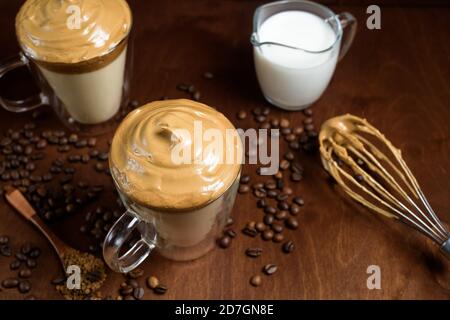 caffè di algone freddo in bicchieri trasparenti su fondo di legno scuro. schiuma di zucchero e caffè istantaneo viene montata con un miscelatore sul latte freddo. Coreano e. Foto Stock