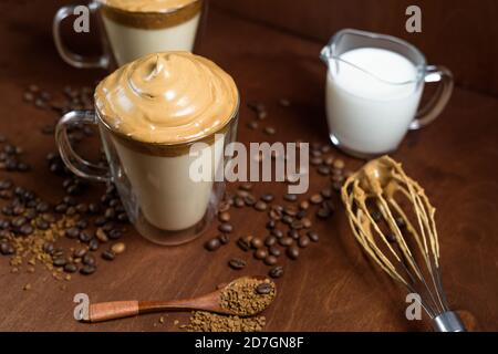 caffè di algone freddo in bicchieri trasparenti su fondo di legno scuro. schiuma di zucchero e caffè istantaneo viene montata con un miscelatore sul latte freddo. Coreano e. Foto Stock