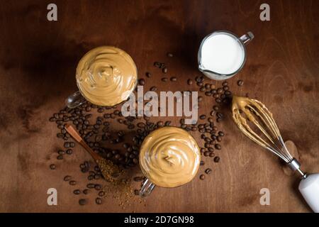 caffè di algone freddo in bicchieri trasparenti su fondo di legno scuro. schiuma di zucchero e caffè istantaneo viene montata con un miscelatore sul latte freddo. Coreano e. Foto Stock