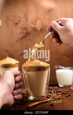 caffè di algone freddo in bicchieri trasparenti su fondo di legno scuro. schiuma di zucchero e caffè istantaneo viene montata con un miscelatore sul latte freddo. Coreano e. Foto Stock