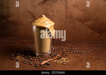 caffè di algone freddo in bicchieri trasparenti su fondo di legno scuro. schiuma di zucchero e caffè istantaneo viene montata con un miscelatore sul latte freddo. Coreano e. Foto Stock