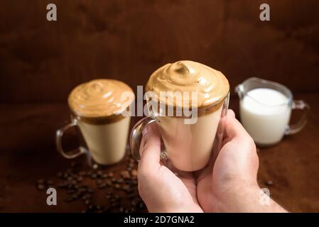 caffè di algone freddo in bicchieri trasparenti su fondo di legno scuro. schiuma di zucchero e caffè istantaneo viene montata con un miscelatore sul latte freddo. Coreano e. Foto Stock