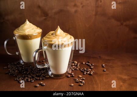 caffè di algone freddo in bicchieri trasparenti su fondo di legno scuro. schiuma di zucchero e caffè istantaneo viene montata con un miscelatore sul latte freddo. Coreano e. Foto Stock