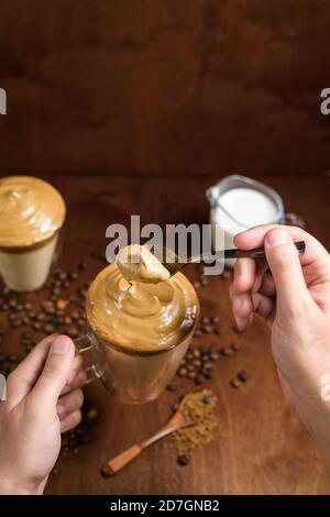 caffè di algone freddo in bicchieri trasparenti su fondo di legno scuro. schiuma di zucchero e caffè istantaneo viene montata con un miscelatore sul latte freddo. Coreano e. Foto Stock