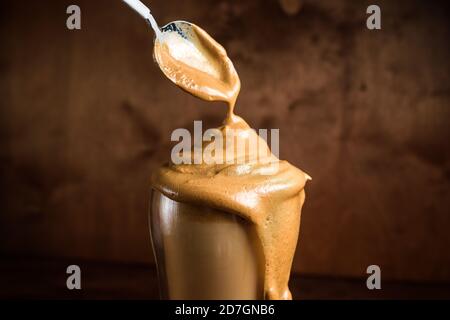 caffè di algone freddo in bicchieri trasparenti su fondo di legno scuro. schiuma di zucchero e caffè istantaneo viene montata con un miscelatore sul latte freddo. Coreano e. Foto Stock