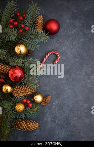 Sfondo di Natale di rami di abete, palle e caramelle di Natale, coni di pino. Sfondo scuro su entrambi i lati . la vista dall'alto Foto Stock