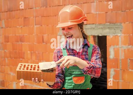 lay bricks. ingegnere teen è lavoratore di costruzione. Artigiano o operaio professionista. International workers day. Ragazza in casco gioca costruttore con mattone. Costruire una casa. Costruzione di capretti. Foto Stock