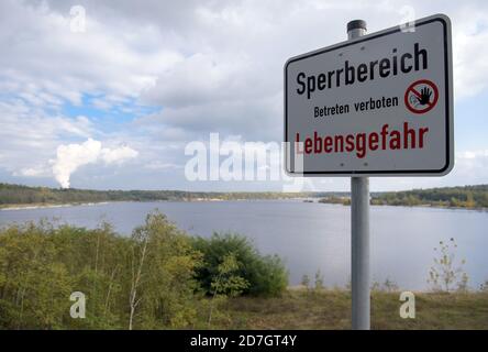 19 ottobre 2020, Sassonia, Elsterheide/OT Bluno: Un segno con l'iscrizione 'Sperrbereich Lebensgefahr' (pericolo di vita) si trova sulla riva del Sabrodter See. Il villaggio si trova nel mezzo della zona di carbone marrone. L'estrazione del carbone è stata abbandonata nel 1991 e i fori rimanenti sono stati allagati. Come parte del Lakeland lusaziano, Bluno si trova sul Sabrodter See e il Blunoer Südsee. Foto: Soeren Stache/dpa-Zentralbild/ZB Foto Stock