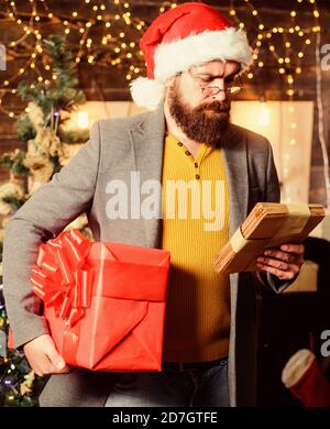 Uomo Barbuto hipster usura santa hat tenere mazzetto di lettere e confezione regalo. Uomo Barbuto con occhiali lettura posta per santa. Spirito di miracolo d'inverno. Post per babbo natale. Lettera a Babbo Natale. Foto Stock