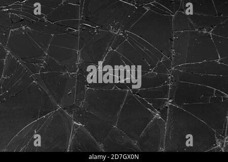 Sfondo nero con struttura in vetro fessurato. Incrinatura sul vetro. Schermo rotto. Telefono scuro rotto. Incrinature bianche nel vetro Foto Stock