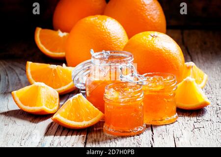 Gustosa marmellata d'arancia fatta in casa e arance fresche, sfondo in legno vintage, fuoco selettivo Foto Stock