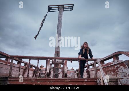 Una donna pirata in una bandana siede con un coltello in mano sul ponte di  legno di una nave Foto stock - Alamy