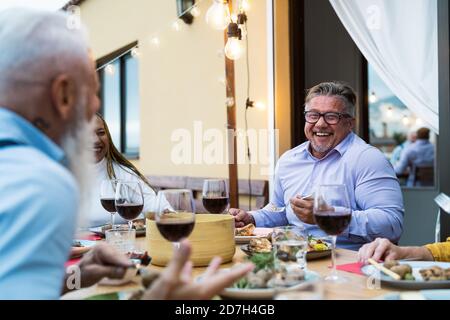 Amici anziani felici che si divertono a cenare insieme sul patio della casa - concetto di stile di vita per gli anziani e gli alimenti Foto Stock