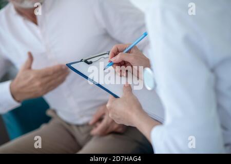 Primo piano delle mani del medico femmina che prendono appunti Foto Stock