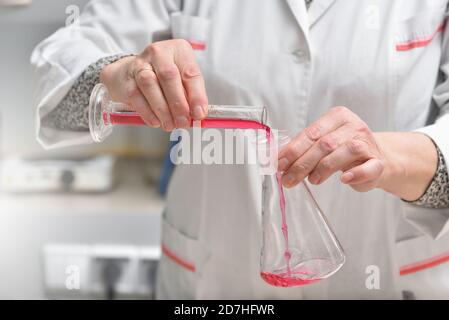 l'assistente di laboratorio versa il liquido in un primo piano della provetta Foto Stock