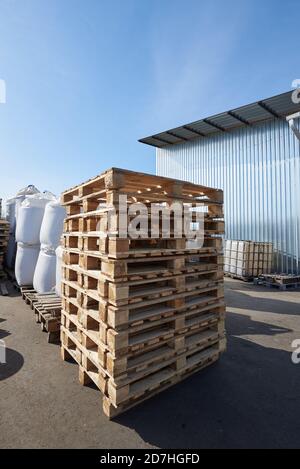 Vecchi pallet in legno impilati all'esterno in magazzino Foto Stock