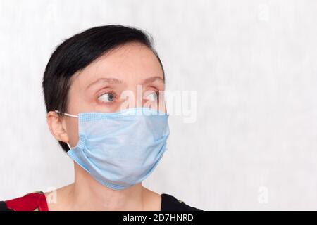 Ritratto di una donna che indossa una maschera medica usa e getta durante la pandemia del coronavirus. Foto Stock