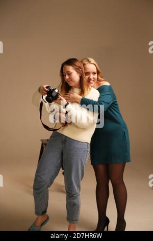 Due ragazze si abbracciano in uno studio fotografico. Il fotografo guarda le foto. Yaroslavl Russia 10.10.2019 Foto Stock