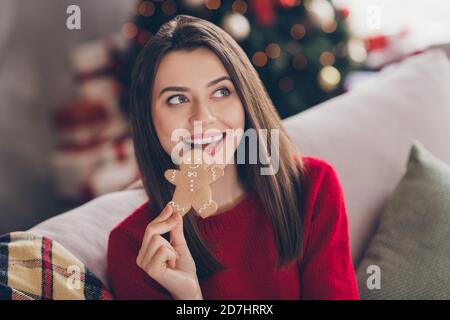 Ritratto di positivo ragazza mangiare x-mas gustoso uomo forma zenzero biscotto di pane in casa al chiuso con ponticello rosso Foto Stock