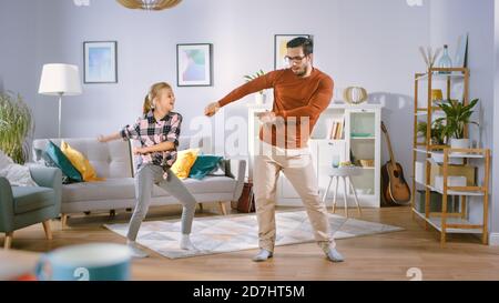 Happy Little Girl balla con il giovane Padre nel mezzo del salotto. Happy Family Time, Padre e figlia Dancing a casa. Foto Stock