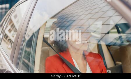 Bella giovane donna ride su un sedile passeggero di un'auto, guarda in Wonder fuori dalla finestra. Telecamera montata all'esterno dell'auto in movimento. Foto Stock