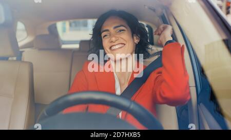 Ritratto di bella donna che guida l'auto, ha divertimento, ascolta la musica. Ripresa con fotocamera dal parabrezza anteriore. Foto Stock