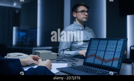 Il giovane bel sospetto durante l'interrogazione subisce il test POLIGRAFO rilevatore di Lie, collegato alla macchina risponde alle domande. Viene visualizzato il computer Foto Stock