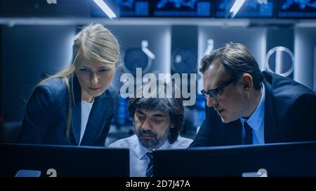 Operatori maschili e femminili che lavorano su computer nella sala di controllo del sistema. Gli analisti delle agenzie governative segrete stanno facendo ricerche, conducendo la sicurezza informatica Foto Stock