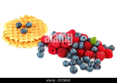 Mirtilli freschi e lamponi, biscotti da waffle con un cucchiaio di legno isolato su sfondo bianco. Foto Stock