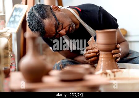 Primo piano di un artista maschile che fa la terracotta su ruota in ceramica officina Foto Stock