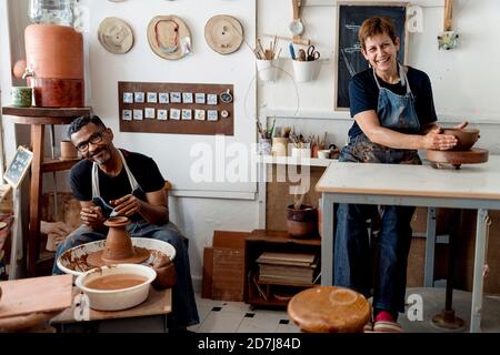 Sorridenti vasai maschi e femmine che lavorano in officina Foto Stock